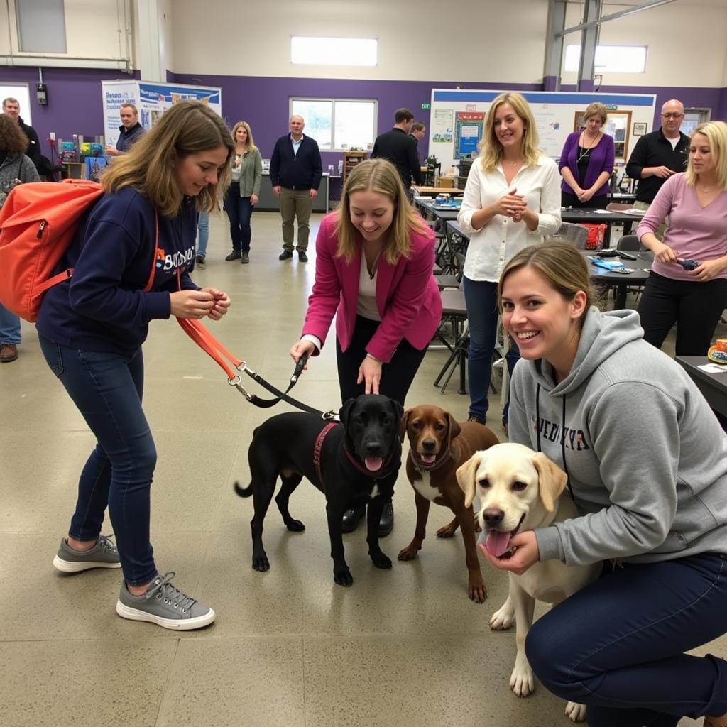 Smiling volunteers at the Humane Society Zionsville adoption event, interacting with dogs and potential adopters