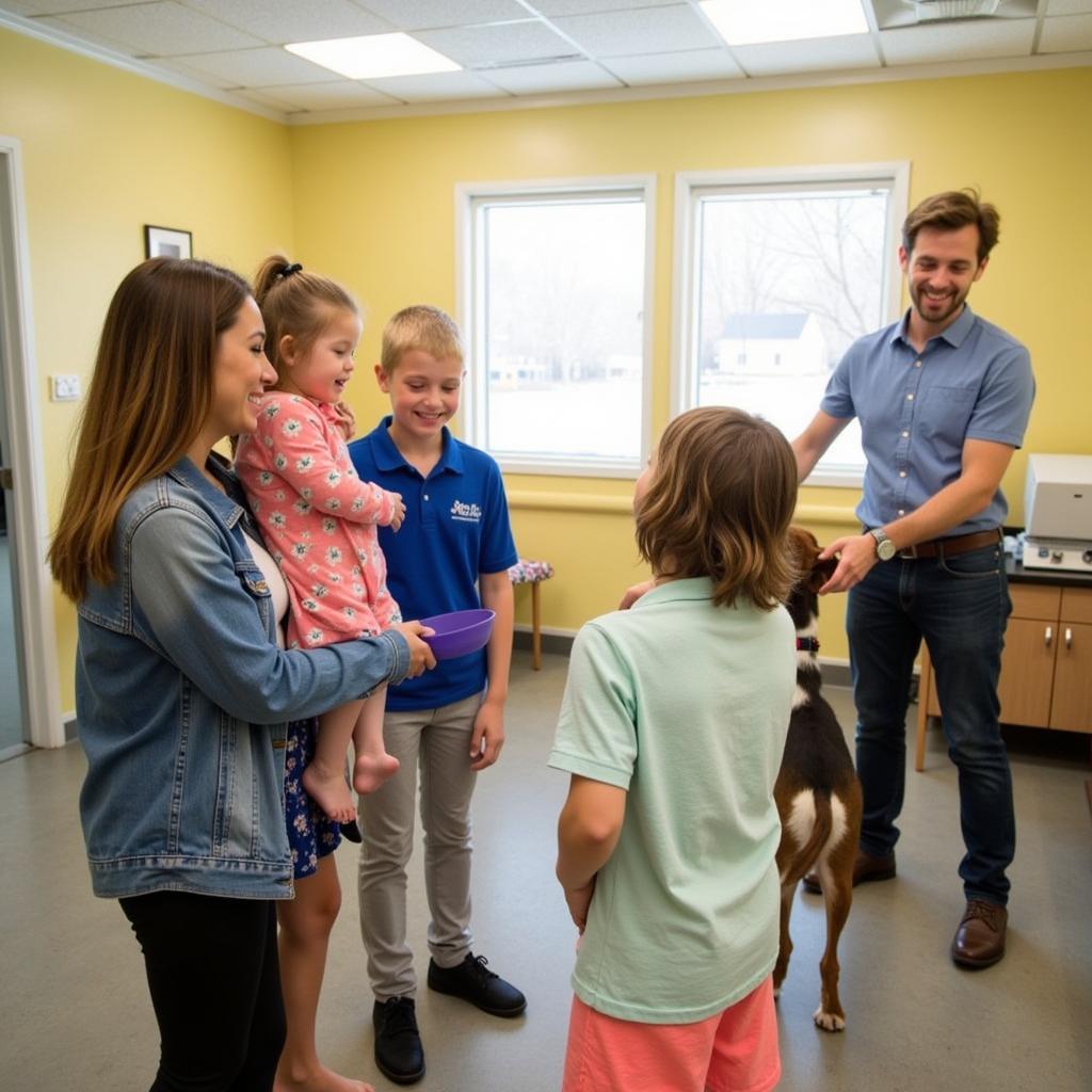 A family meeting a playful dog in a spacious, comfortable meet-and-greet room at the Humane Society Zionsville