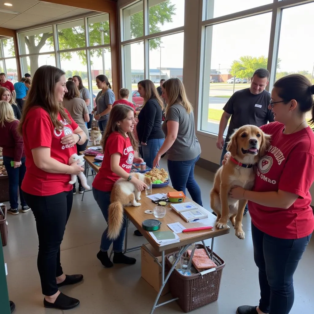 Volunteers and families interacting with adoptable dogs at a Neosho MO Humane Society adoption event