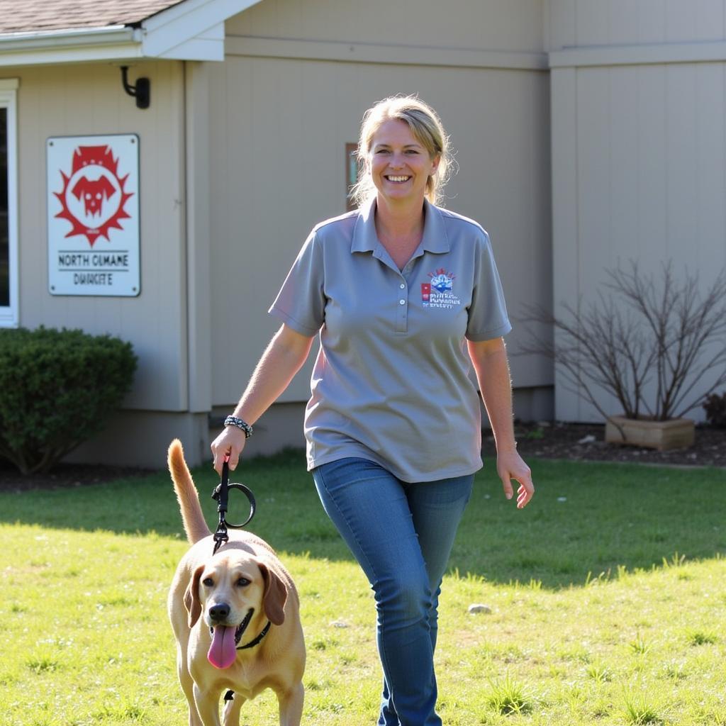 A volunteer walks a happy dog outside the North Country Humane Society