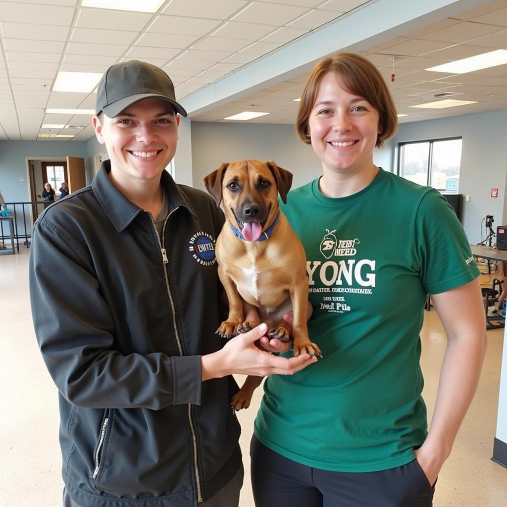 A volunteer smiles brightly while playing with a playful puppy at the Minot Humane Society. 